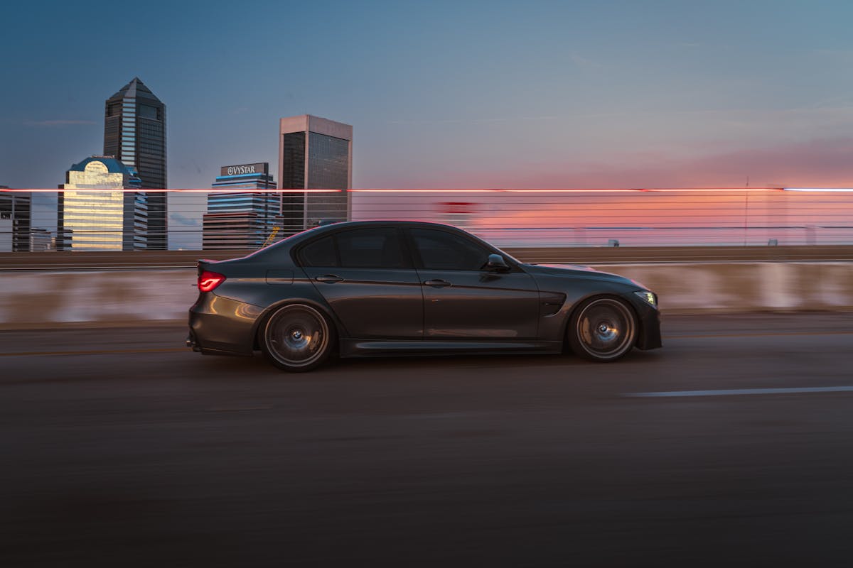 Black sedan cruising on a city highway at dusk